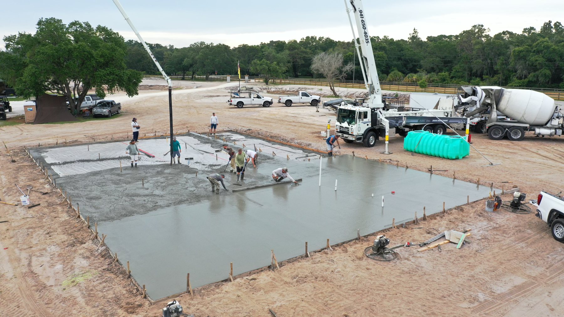 Crew finishing a large house slab with a concrete boom pump